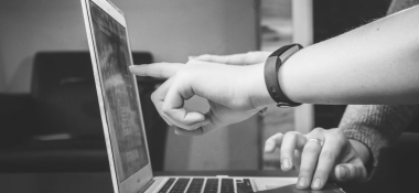 A person showing something on a laptop to another person