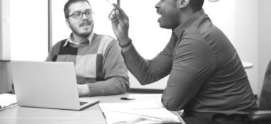 two people working on laptopn and talking